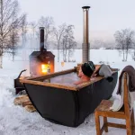 Vue latérale de l'extérieur isolé de la baignoire Hikki Bohemen chauffée au bois dans un paysage enneigé