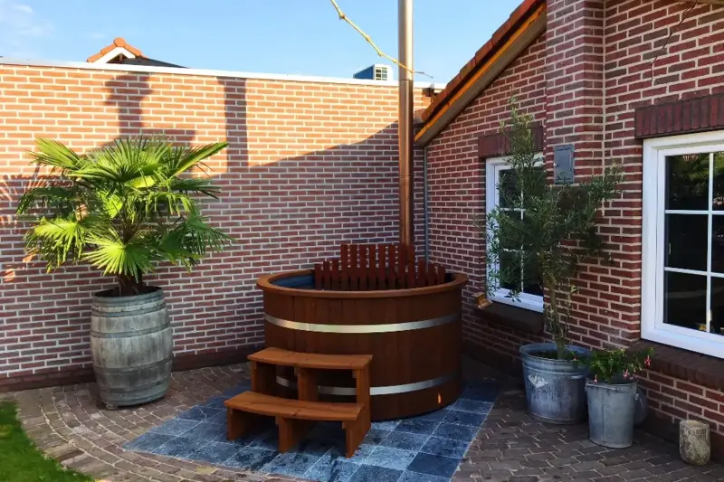 Bain nordique Ticra en Thermowood avec poêle interne, rebord en bois et escalier assorti