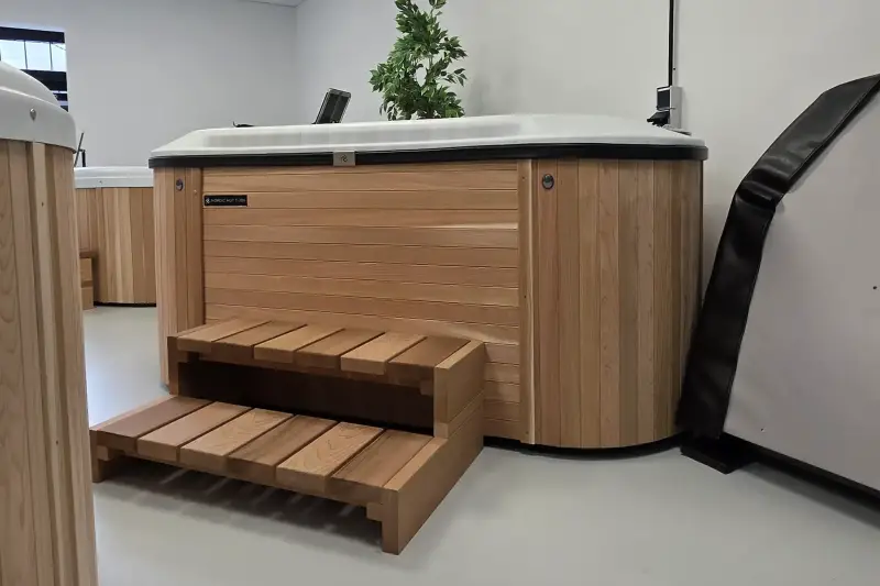 Side view of Nordic Hottub Bella with red cedar finish, steps and insulated cover in showroom