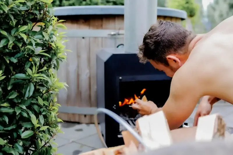 Man die externe houtgestookte hottubkachel opstookt in de tuin