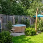 Bain nordique Nordic Hottub Classic avec finition en cèdre rouge et cuve intérieure en plastique HDPE dans un jardin verdoyant