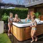 Personnes profitant d’un bain nordique Nordic Hottub Spa avec finition en cèdre rouge dans le jardin