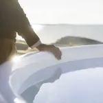 Homme à côté du bain nordique Skargards Rojal avec poêle intégré au coucher du soleil