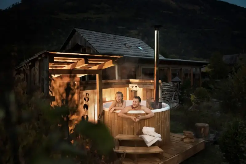 Stel geniet in het avondlicht van de stomende Skargards Panel hottub met interne kachel