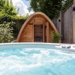 Bain nordique Nordic Hottub Classic bouillonnant avec sauna Red Cedar Pod en arrière-plan
