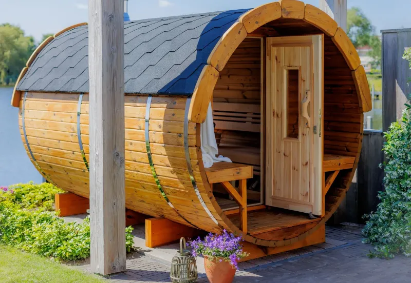 Fasssauna mit Außenveranda und Holztür.