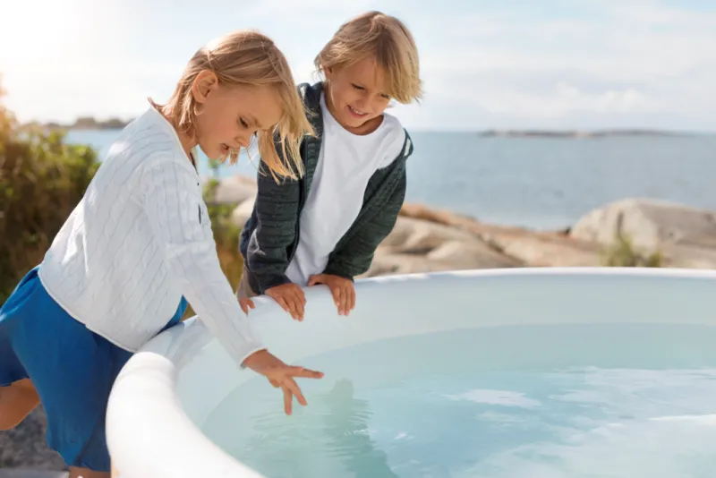 Kinderen die hun vingers in de hottub dippen.