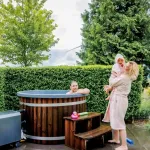 Ticra Thermowood hottub met externe 45 kW houtgestookte kachel en blij gezin in de tuin