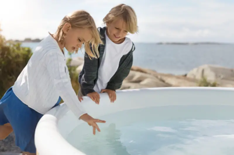 Enfants jouant près du bain nordique sécurisé Skargards Rojal avec poêle intégré
