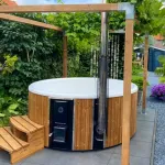 Bain nordique Skargards Rojal avec poêle intégré installé dans un jardin rénové