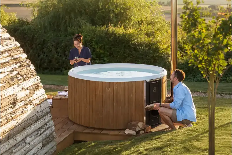 Bain nordique Skargards Rojal avec poêle intégré dans un jardin ensoleillé