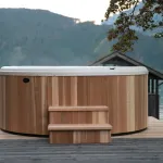 Vue avant du bain nordique Nordic Hottub Classic avec finition en cèdre rouge et marches en cèdre rouge dans la nature