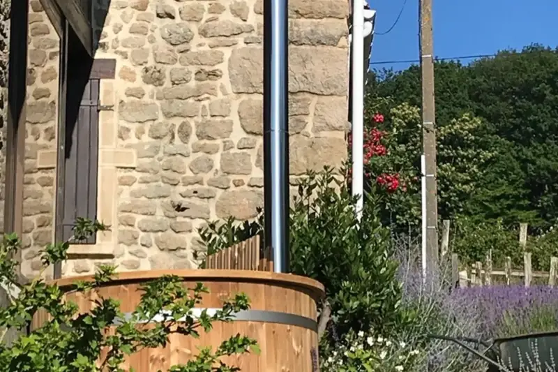 Bain nordique Ticra en Thermowood avec poêle interne installé dans un jardin ensoleillé