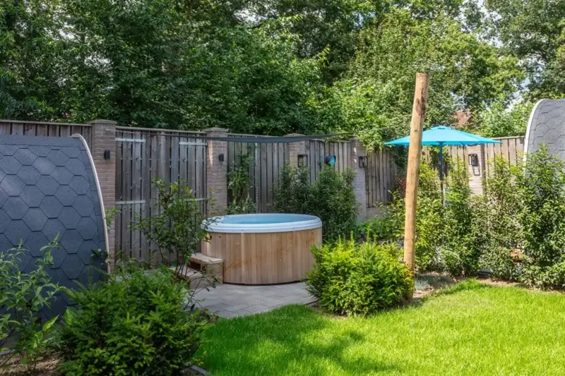 Bain nordique Nordic Hottub Classic avec finition en cèdre rouge et cuve intérieure en plastique HDPE dans un jardin verdoyant