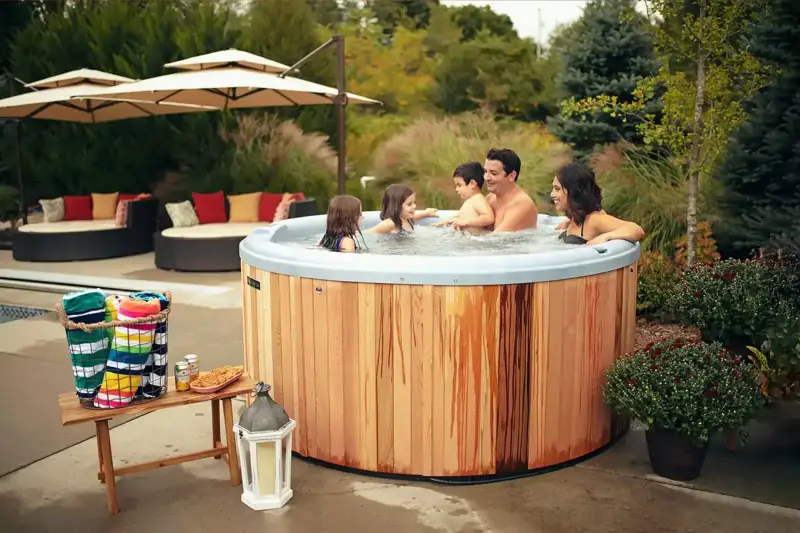 Famille se détend ensemble dans un bain nordique Ticra Classic dans le jardin.