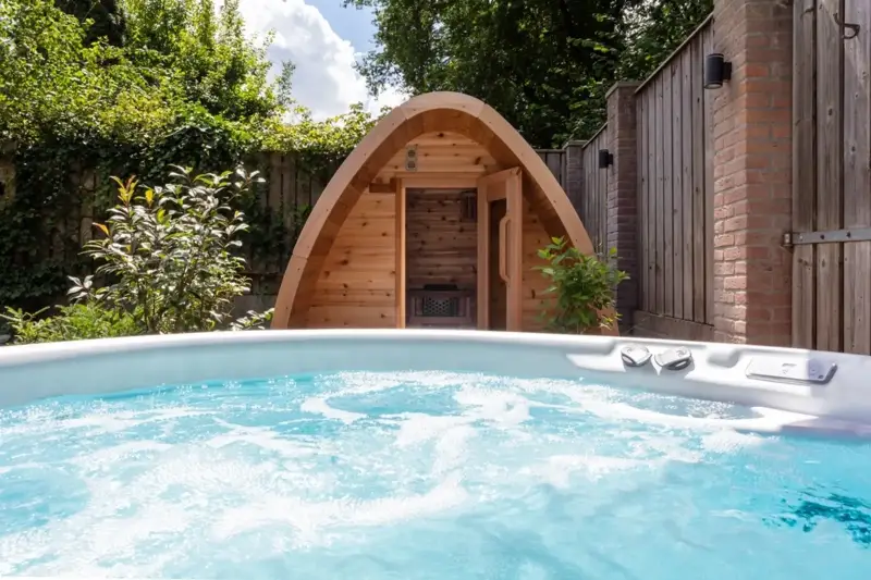 Bain nordique Nordic Hottub Classic bouillonnant avec sauna Red Cedar Pod en arrière-plan