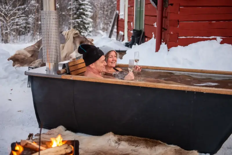 Vue latérale d'un couple profitant du bain nordique Hikki Bohemen dans la neige