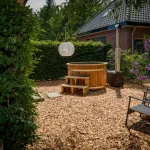 Ticra Thermowood hottub met externe 45 kW houtgestookte kachel in zonnige bloeiende tuin