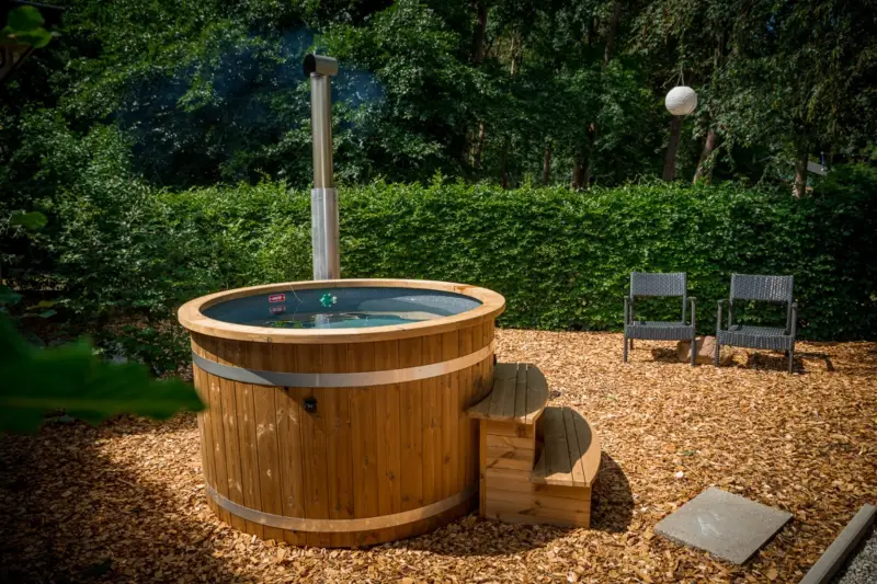 Houtgestookte Ticra Thermowood hottub die wordt verwarmd in een zonnige boerderijtuin