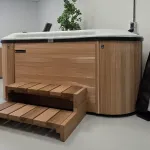 Side view of Nordic Hottub Bella with red cedar finish, steps and insulated cover in showroom