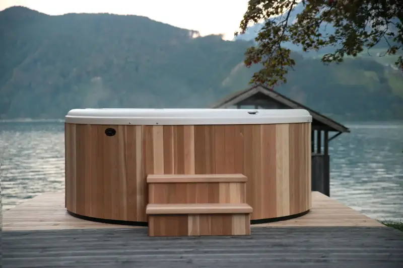 Vue avant du bain nordique Nordic Hottub Classic avec finition en cèdre rouge et marches en cèdre rouge dans la nature