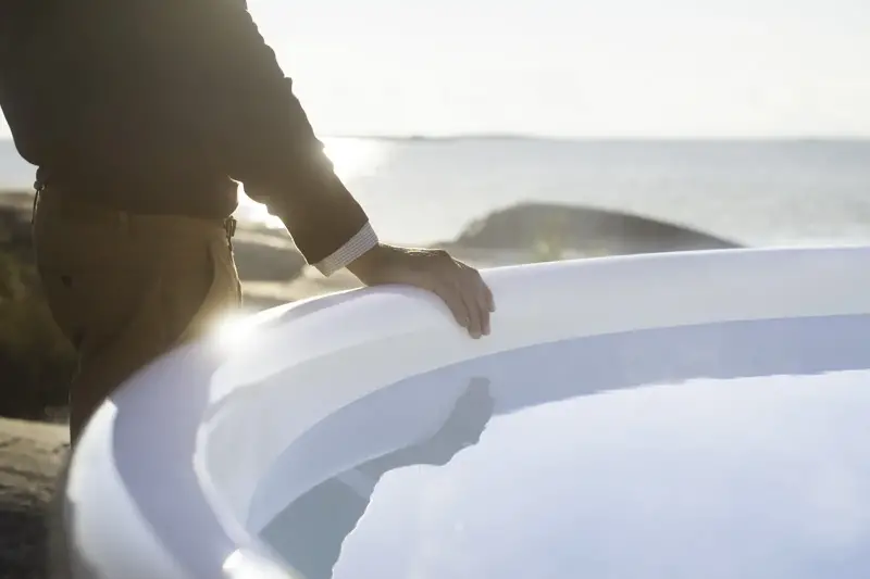 Homme à côté du bain nordique Skargards Rojal avec poêle intégré au coucher du soleil