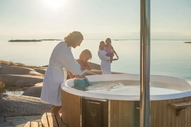 Famille heureuse profitant du bain nordique Skargards Rojal avec poêle intégré