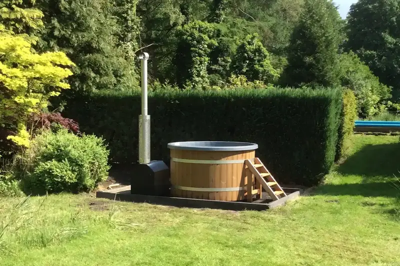 Mooie hottub buiten in de zon met externe houtkachel in de tuin