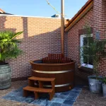 Bain nordique Ticra en Thermowood avec poêle interne, rebord en bois et escalier assorti
