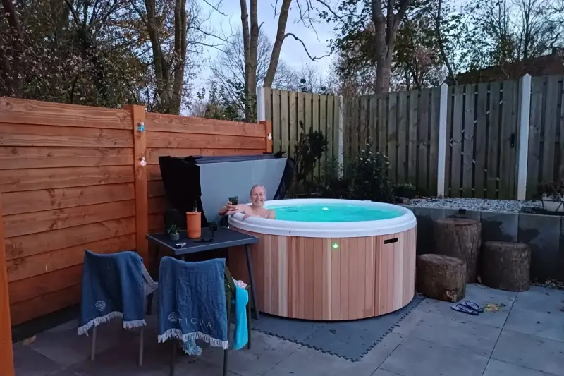 Femme profitant d’un bain nordique Nordic Hottub Classic nouvellement installé avec finition en cèdre rouge et cuve intérieure en plastique HDPE