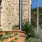 Bain nordique Ticra en Thermowood avec poêle interne installé dans un jardin ensoleillé