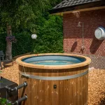 Mooie Ticra Thermowood hottub geplaatst in zonnige boerderijtuin met externe houtgestookte kachel