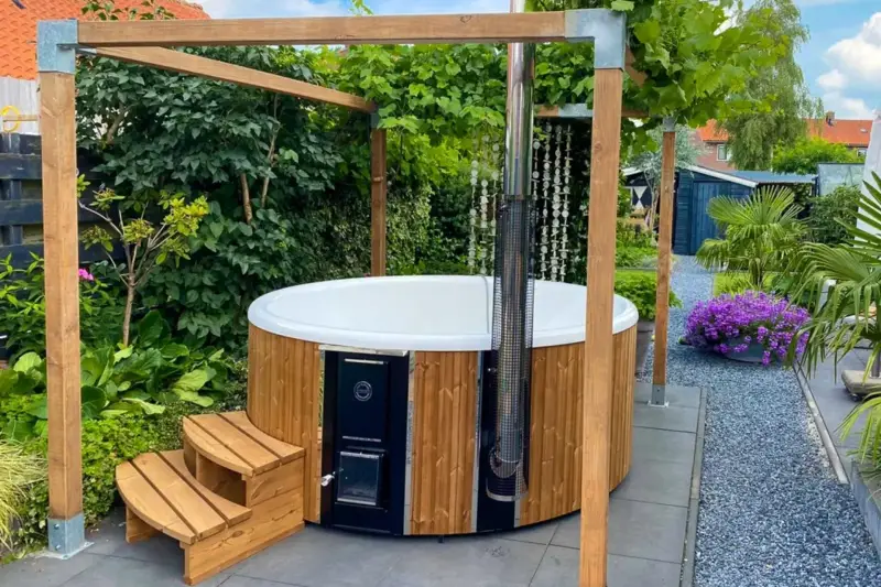 Bain nordique Skargards Rojal avec poêle intégré installé dans un jardin rénové