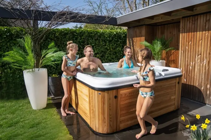 Personnes profitant d’un bain nordique Nordic Hottub Spa avec finition en cèdre rouge dans le jardin