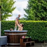 Vader en dochter spelen in warme Ticra Thermowood hottub met externe houtgestookte kachel